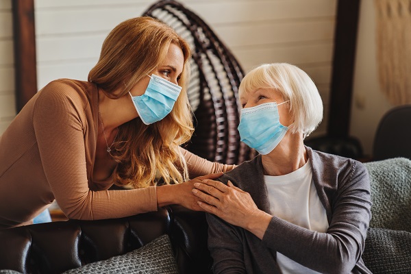 Senior woman with caring daughter at home. Females wearing medical masks.